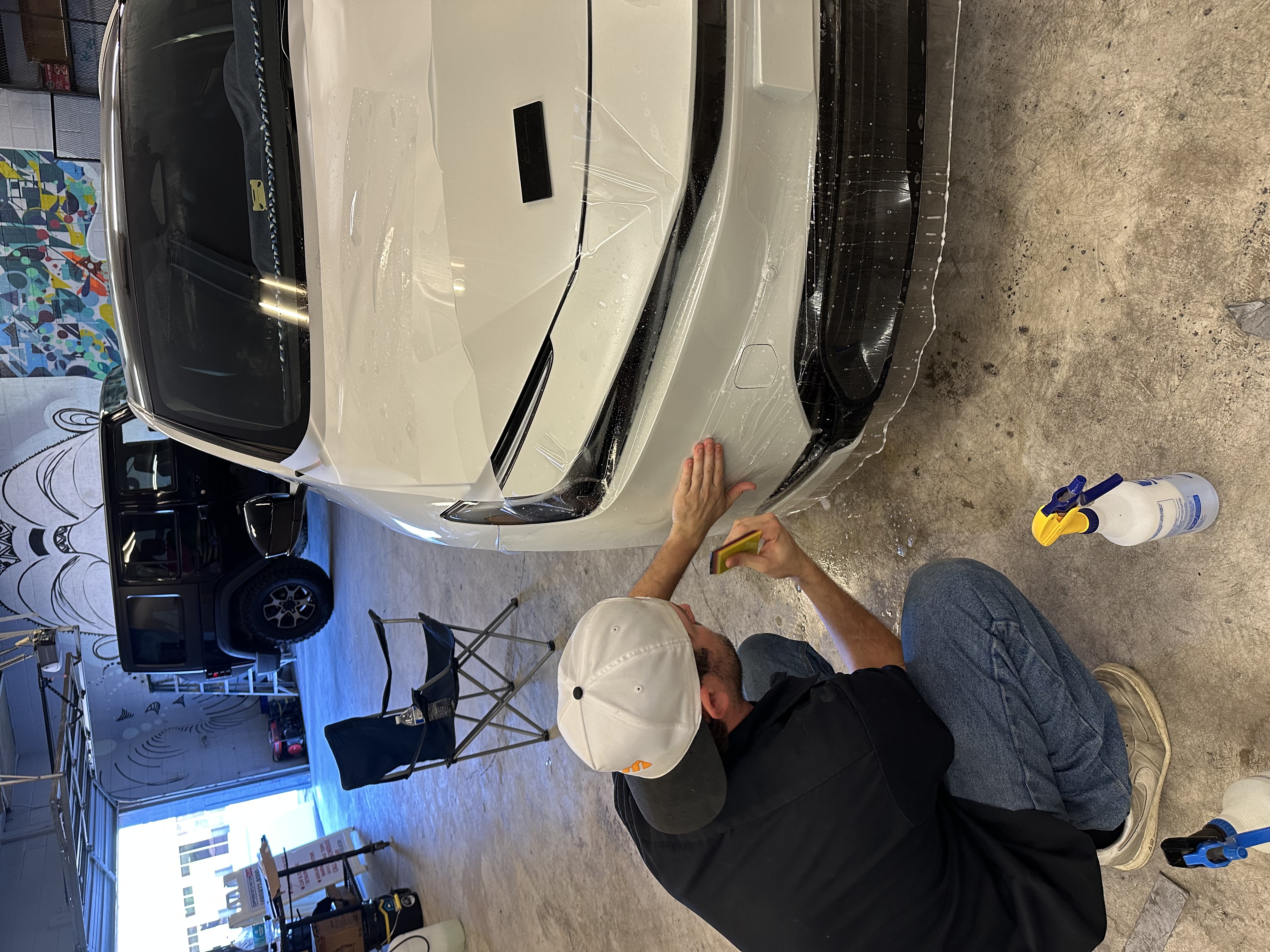 Overhead view of PPF being applied to white vehicle hood