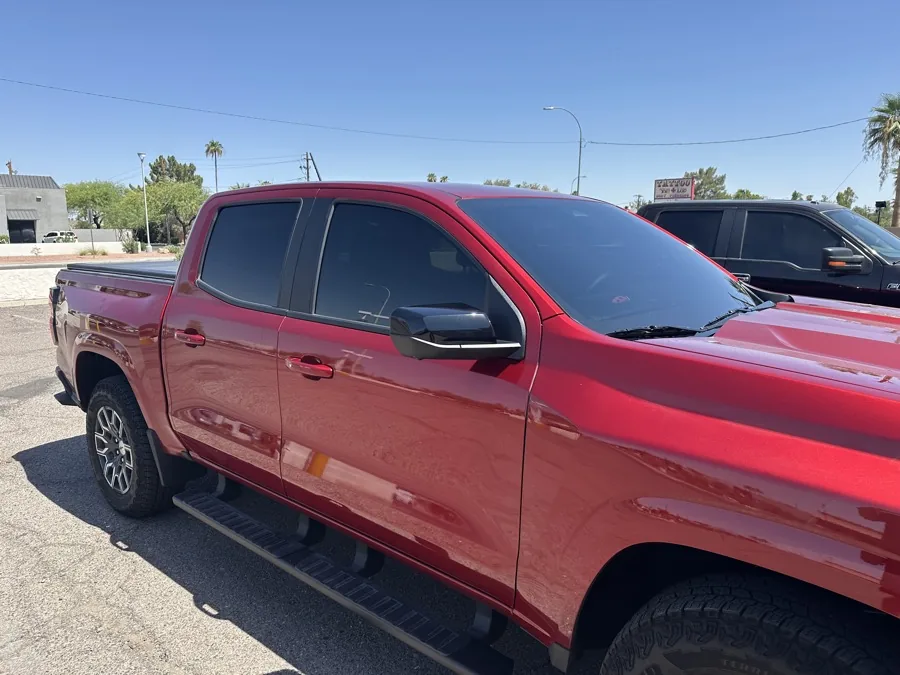Red Chevrolet crew-cab truck with freshly tinted side windows parked in direct Arizona sun outside the Tempe shop