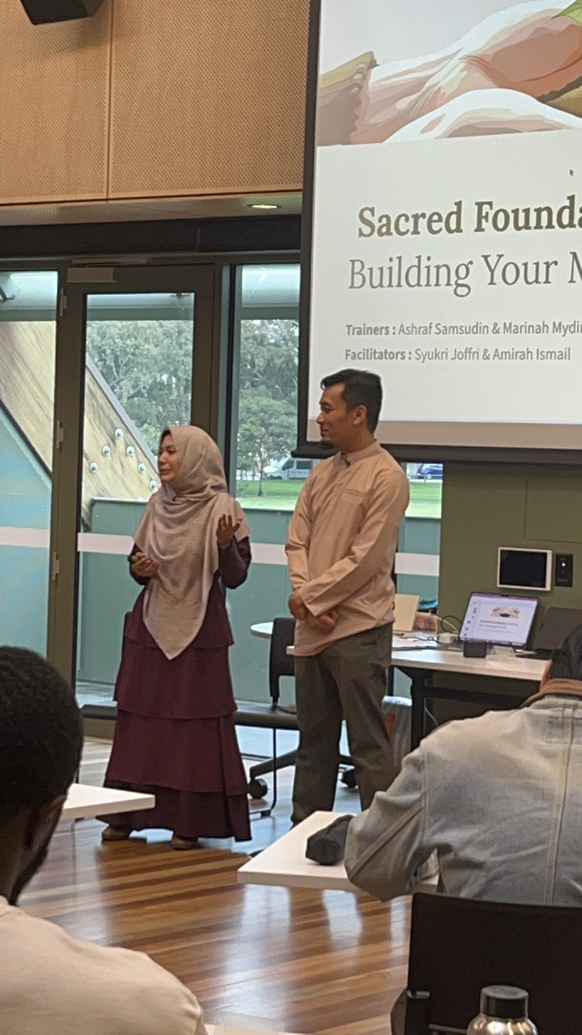 Ashraf and Marinah teaching together at the front of the room