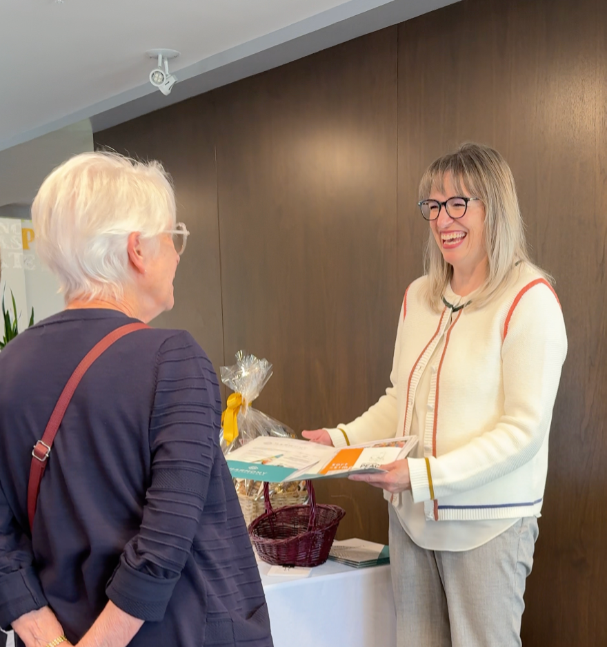 Cathy Cookson handing a gift basket and card to a client after a home sale.