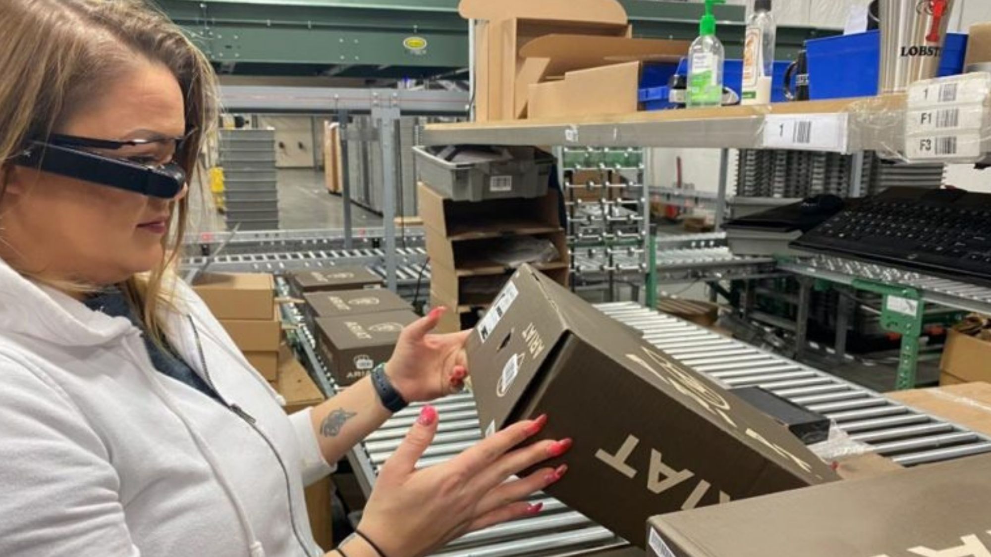 Warehouse operator wearing E2 Vision smart glasses while handling a shoe box