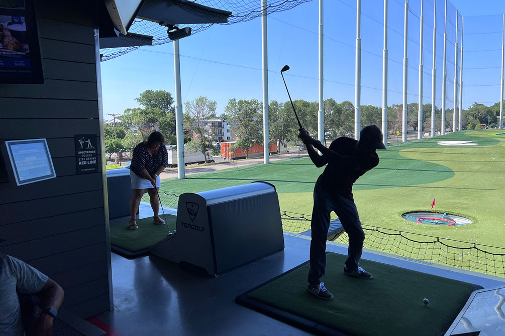 Two Team E2 members hitting golf balls in the Top Golf bays