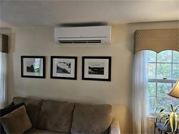 Ductless indoor head unit mounted high on a living room wall above framed pictures