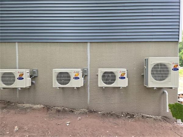 Four Mitsubishi Electric condensers mounted in a row on the wall of a commercial building