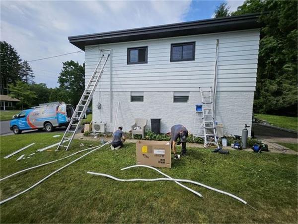K.O. HVAC install day with ladders against a two-story home and equipment staged on the lawn
