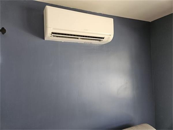 White ductless indoor unit installed on a dark gray bedroom wall