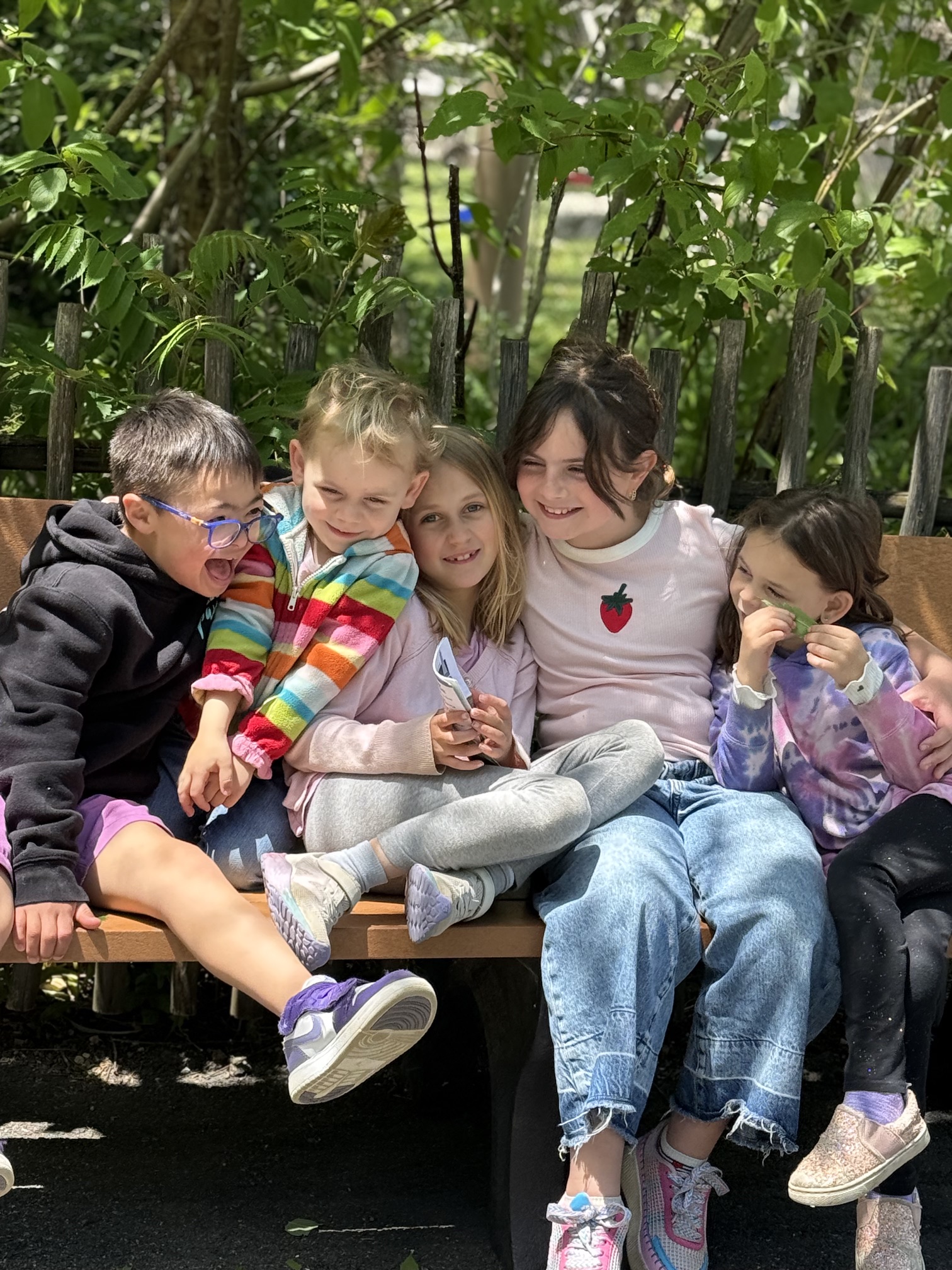 Five Radiant Pathways students laughing together on a bench outside the learning center