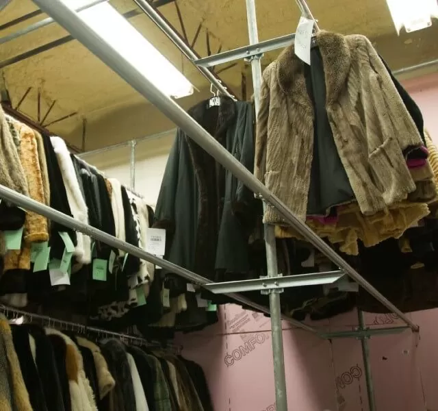 Fur coats hanging on tiered racks in the HSG Furs warehouse