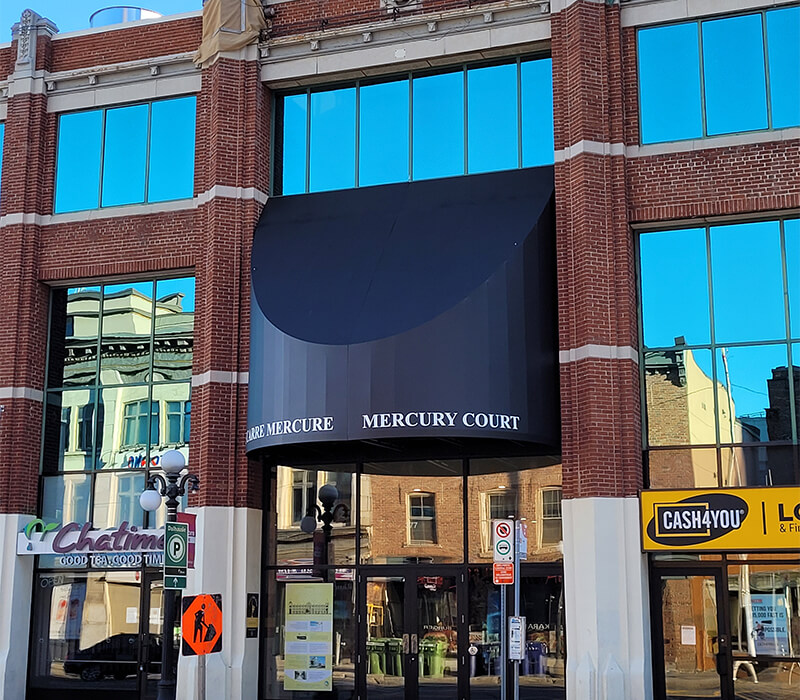 Street view of the Mercury Court building entrance with a dark blue awning