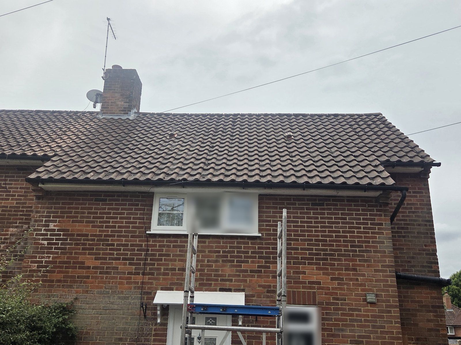 Mobile scaffold tower going up beneath the roofline of a red-brick semi