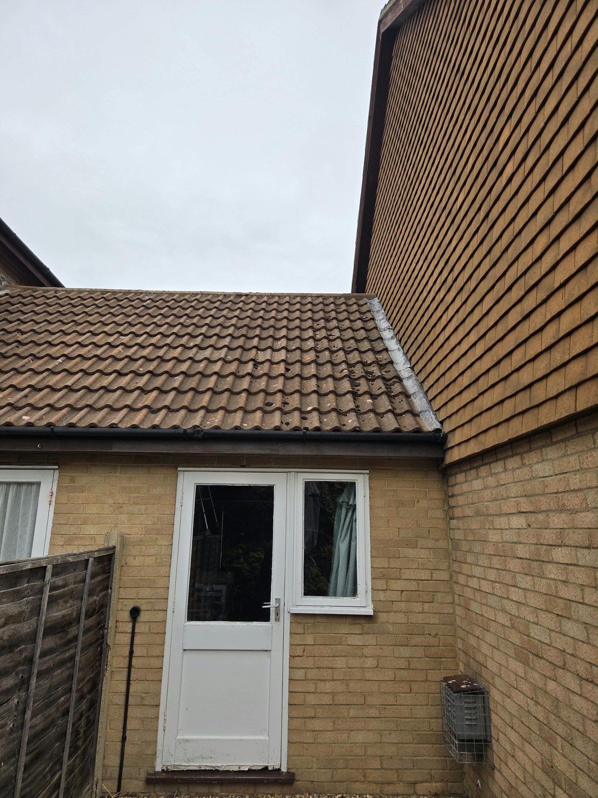 Before: rear extension roof with moss clumps along the lead flashing beside a tile-hung wall