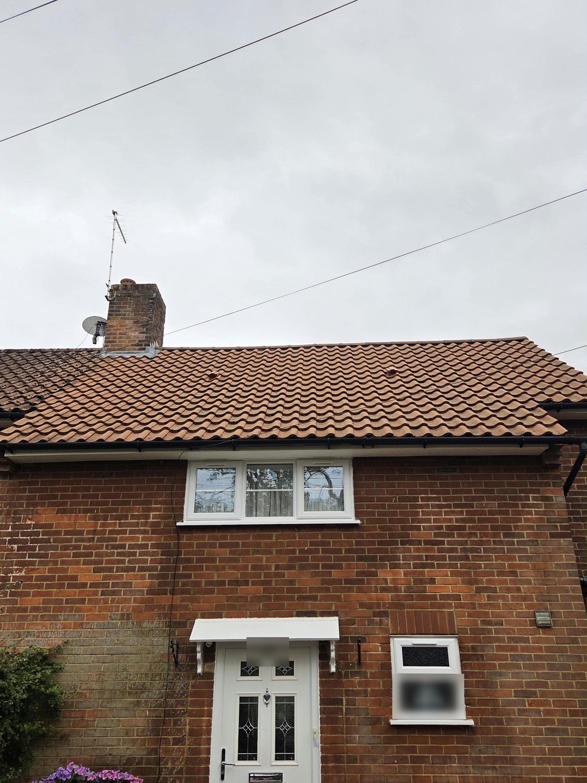 The same semi with its roof cleaned to orange pantiles beside a neighbour's mossy roof