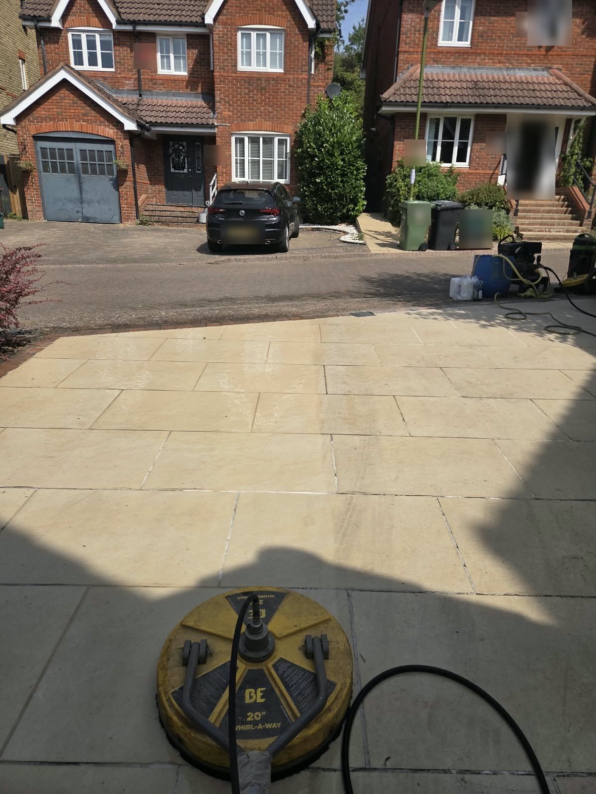 Rotary surface cleaner on a slab driveway, clean slabs ahead beside slabs still to be done