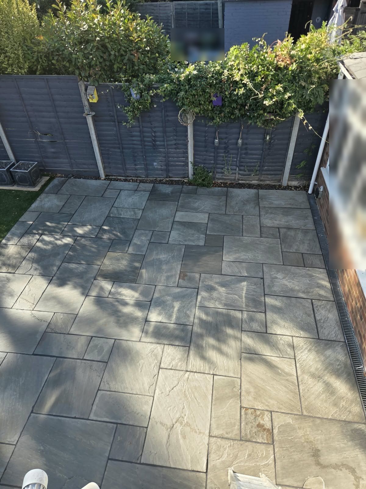 Finished grey sandstone patio seen from an upstairs window, clean slabs beside a drainage channel