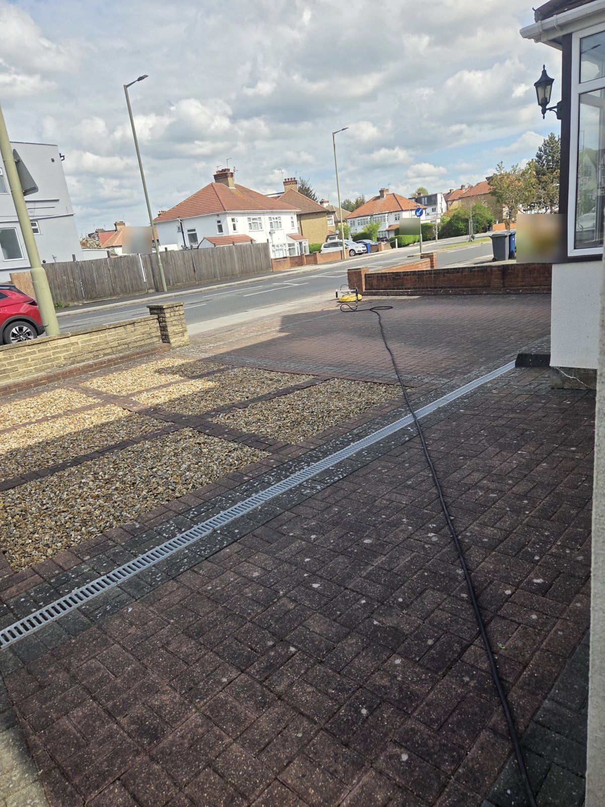 Red block-paved driveway with gravel panels and a channel drain, dull and covered in white lichen spots