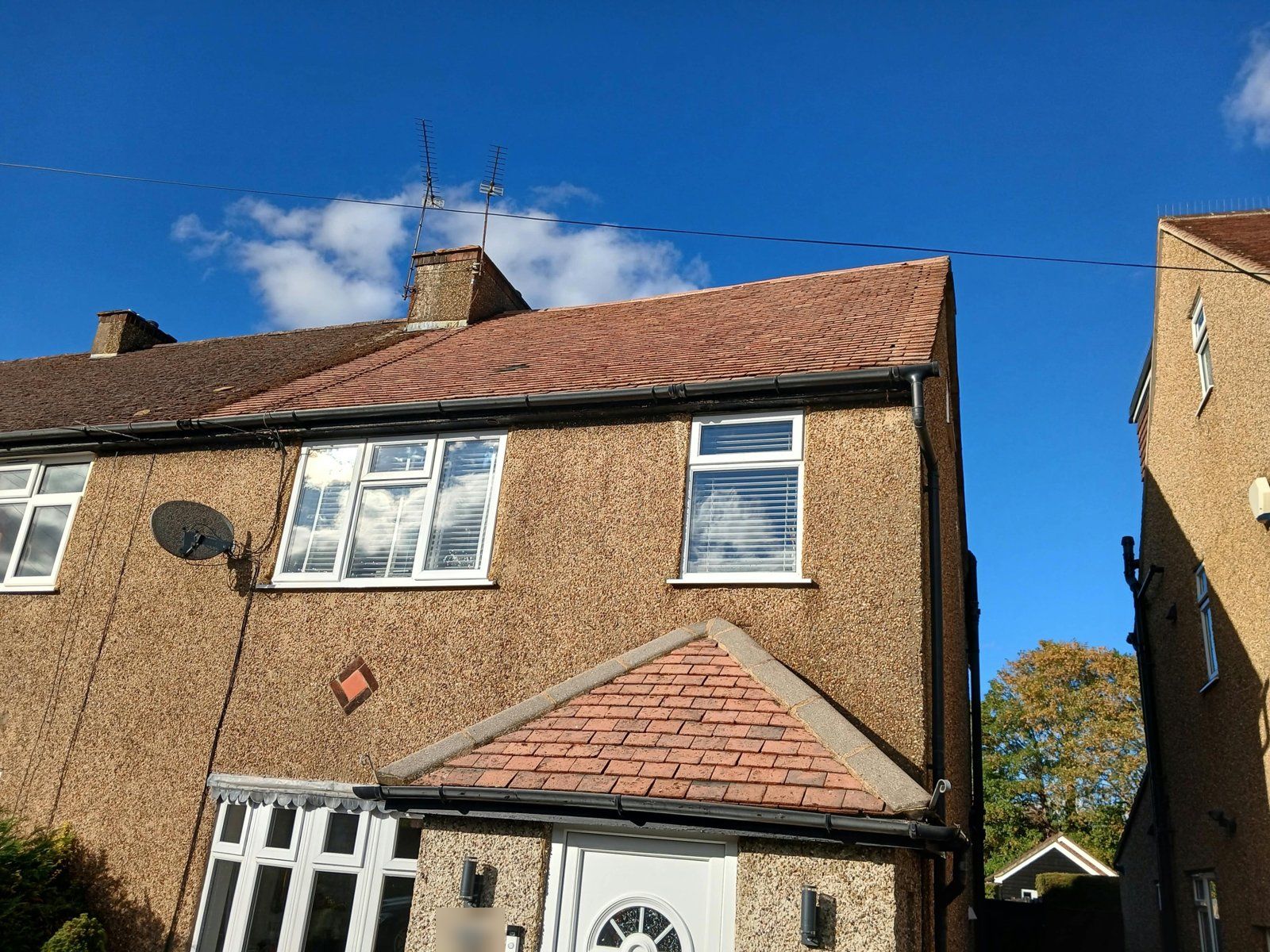 The same semi with the main roof and porch roof cleaned to red tiles, the attached neighbour's roof still darker