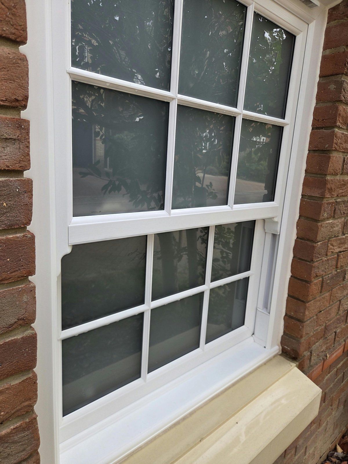 White sash window with a clean frame and glazing bars, water drops still on the bars