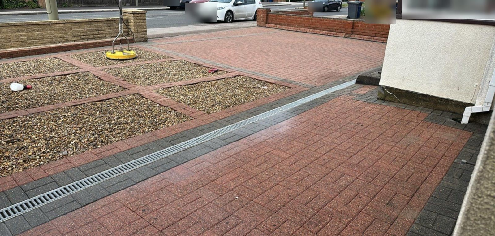 The same block driveway cleaned, red blocks bright and free of lichen spots, with the rotary cleaner on the gravel