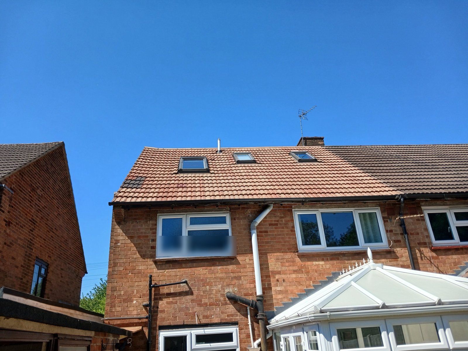 The same rear roof cleaned, terracotta tiles next to the neighbour's dark, mossy roof