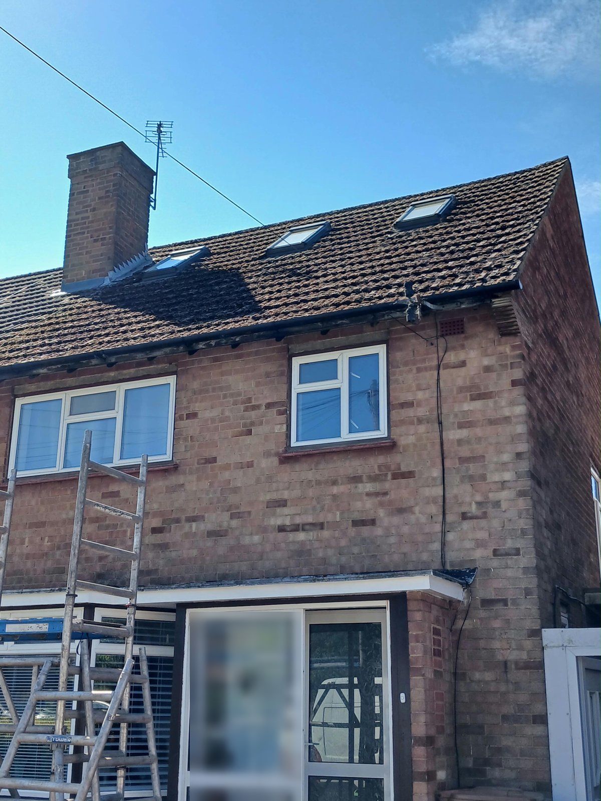Front of the same loft-converted semi with heavy moss on the roof and an access tower going up