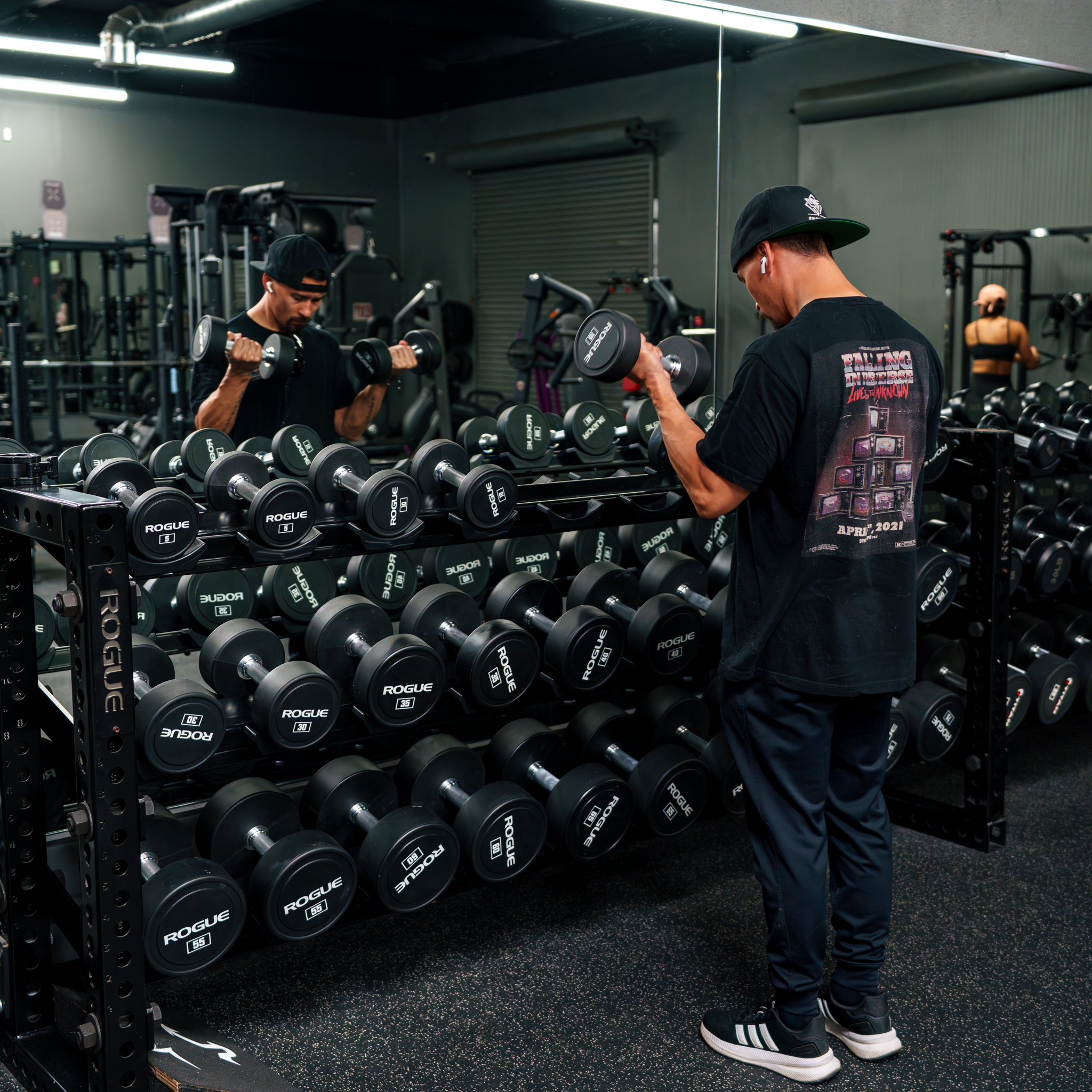 a photo of a client working out, doing dumbbell curls near the barbell rack