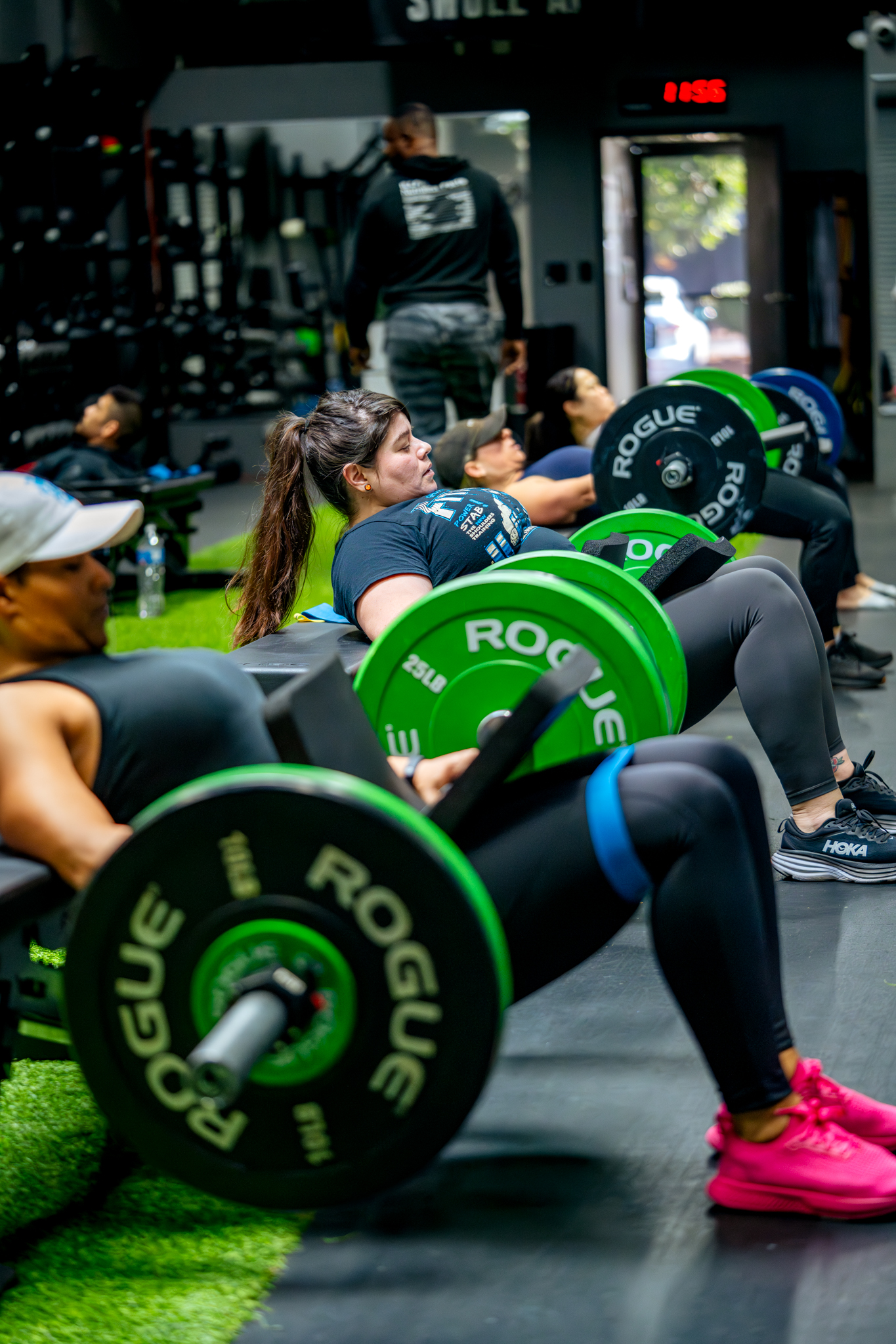 Santa Ana group training pushing each other to work harder while performing hip thrusts Santa Ana group training pushing each other to work harder while performing hip thrusts