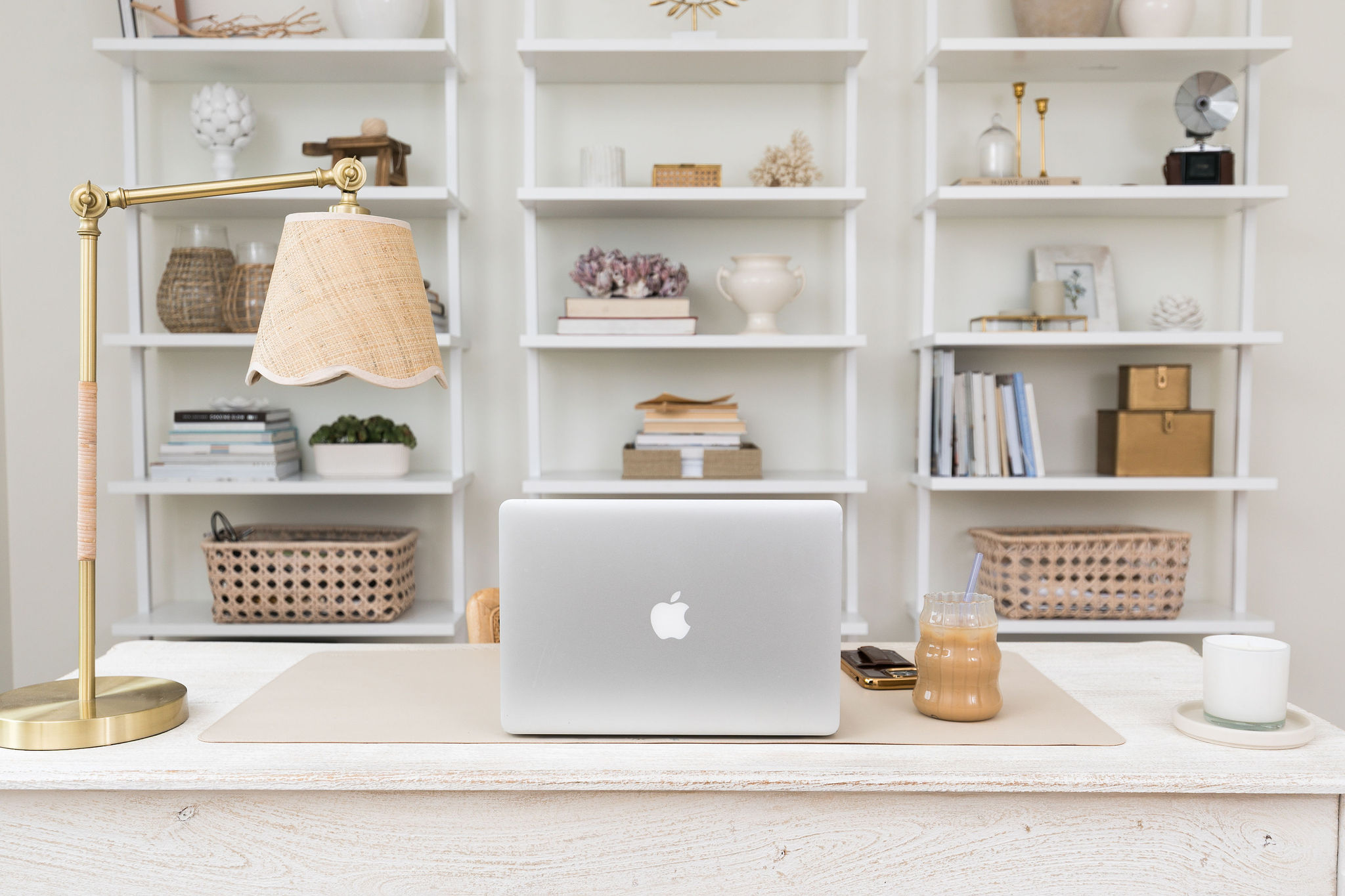 A composed desk before shelves of collected objects