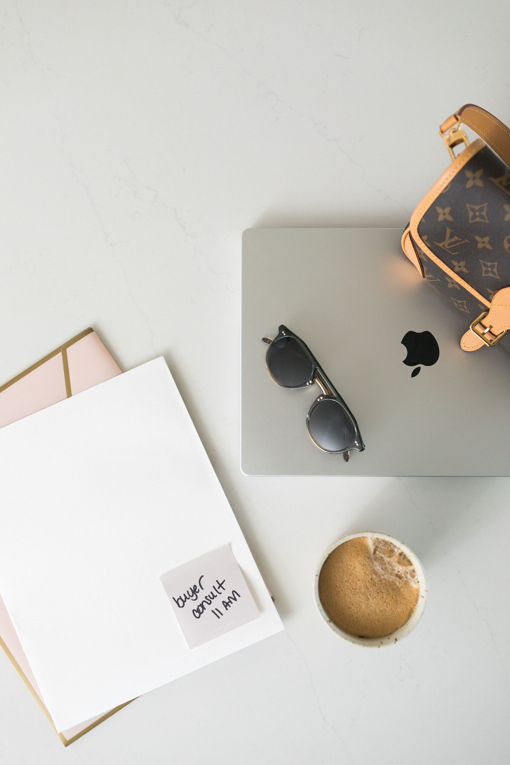 A notepad with a scheduled buyer consult beside coffee