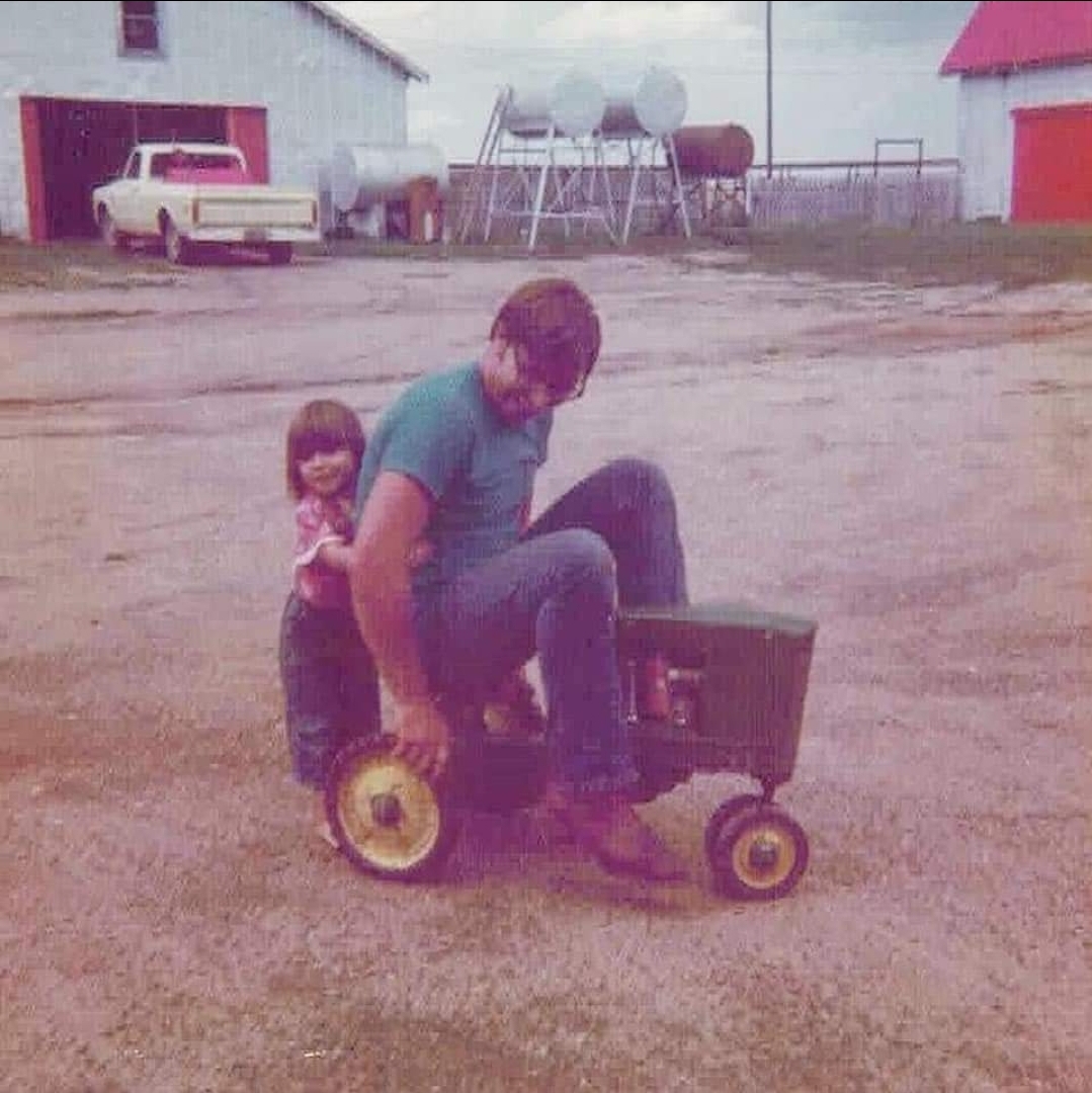 Tara and her dad playing on a toy tractor