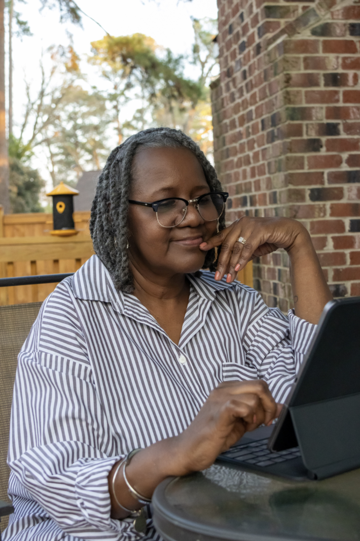 Marie Kirkland sitting outside mindfully writing on iPad