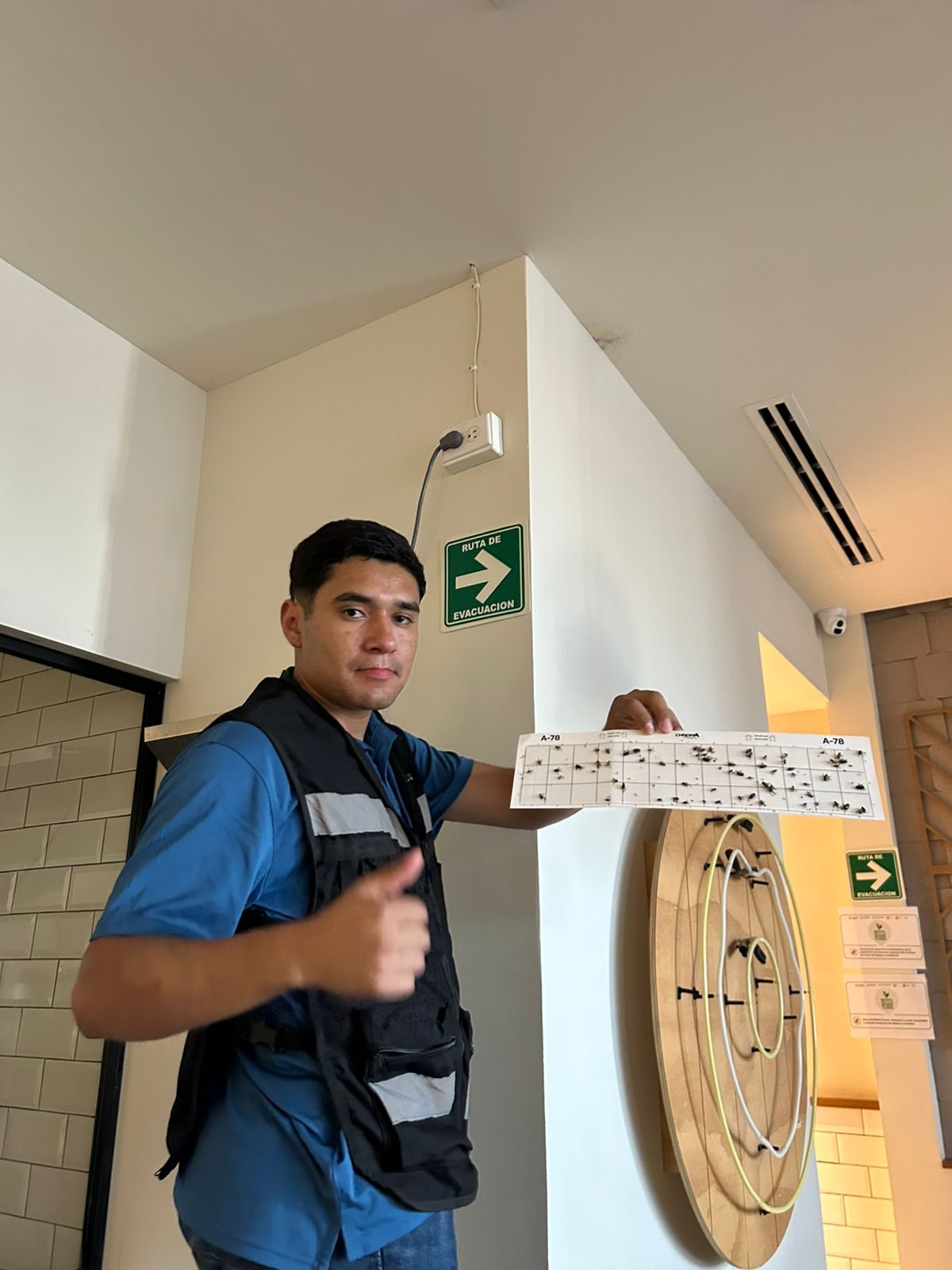 Técnico de SIALSA con chaleco mostrando una trampa de monitoreo de plagas en un restaurante