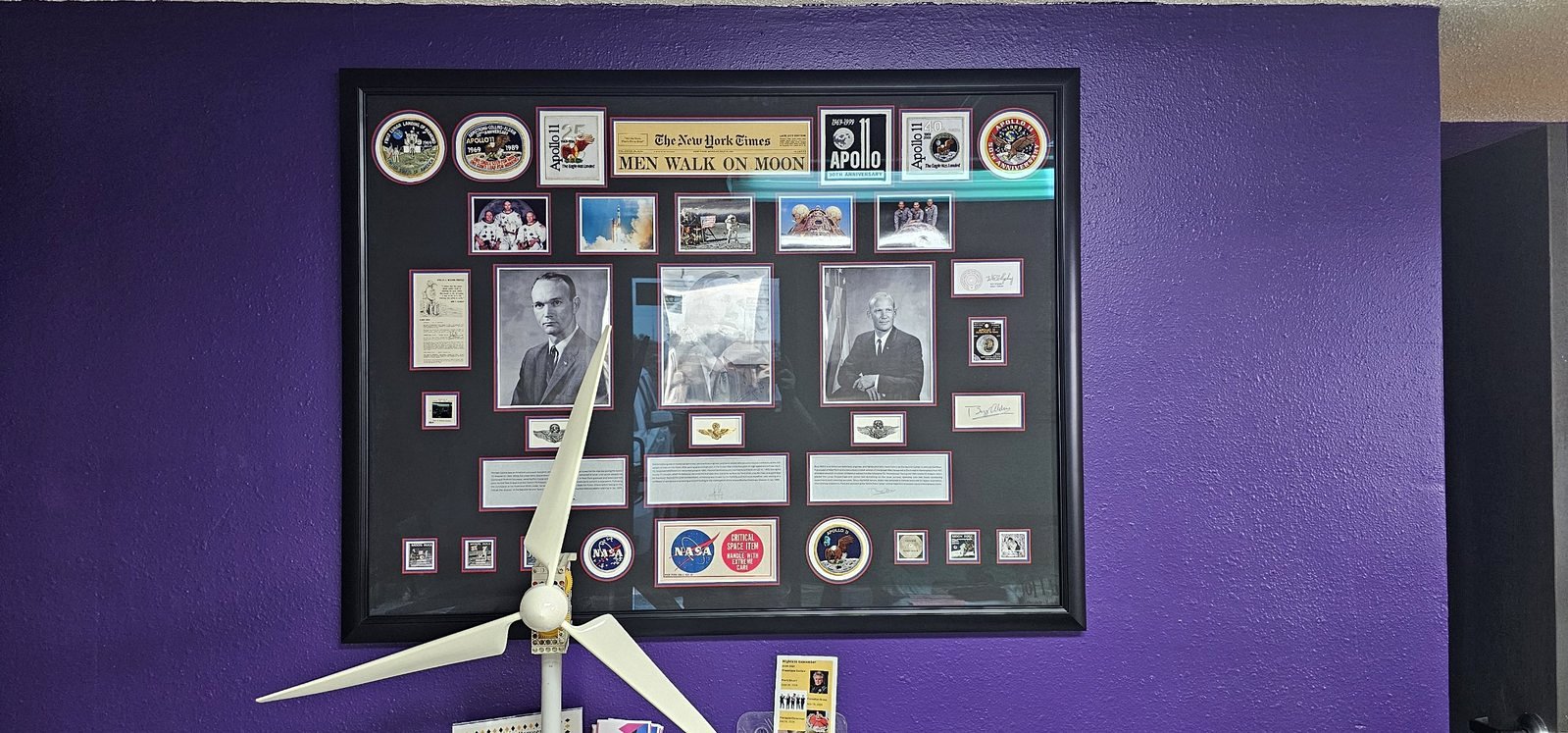 A framed Apollo 11 display with mission patches and astronaut photos on a purple wall at SSES