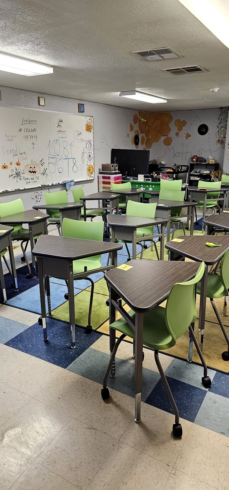A classroom at Sacramento School of Engineering and Science with green chairs, desks on wheels and Halloween drawings on the whiteboard
