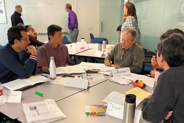 Business team discussing decisions in leadership workshop showing varied interpretation and collaborative problem solving Business team discussing decisions in leadership workshop showing varied interpretation and collaborative problem solving