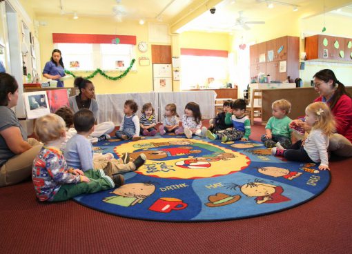 Children sitting in a circle on a rug during Montessori group time