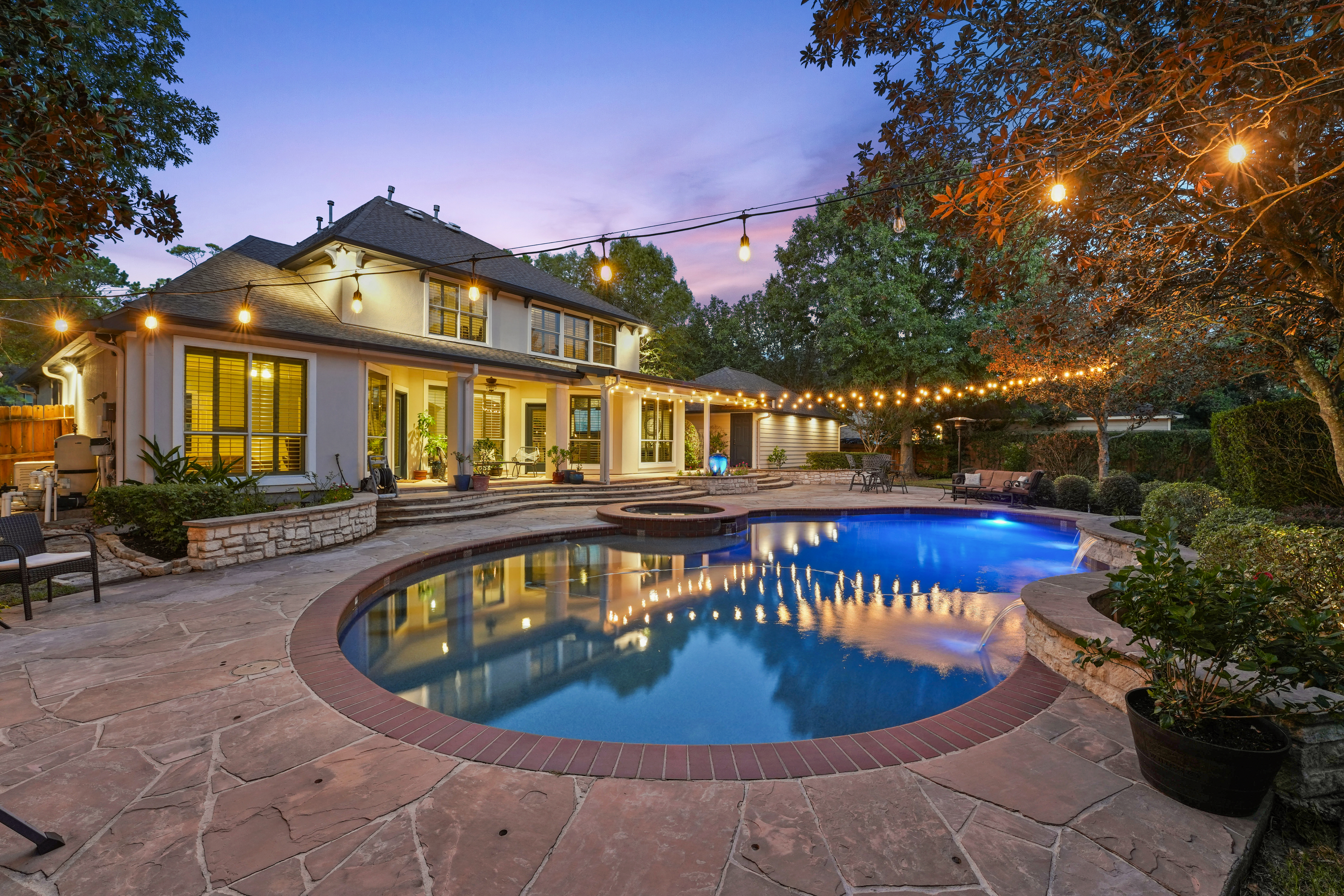 Twilight photo of a luxury home with a lit swimming pool at sunset Twilight photo of a luxury home with a lit swimming pool at sunset