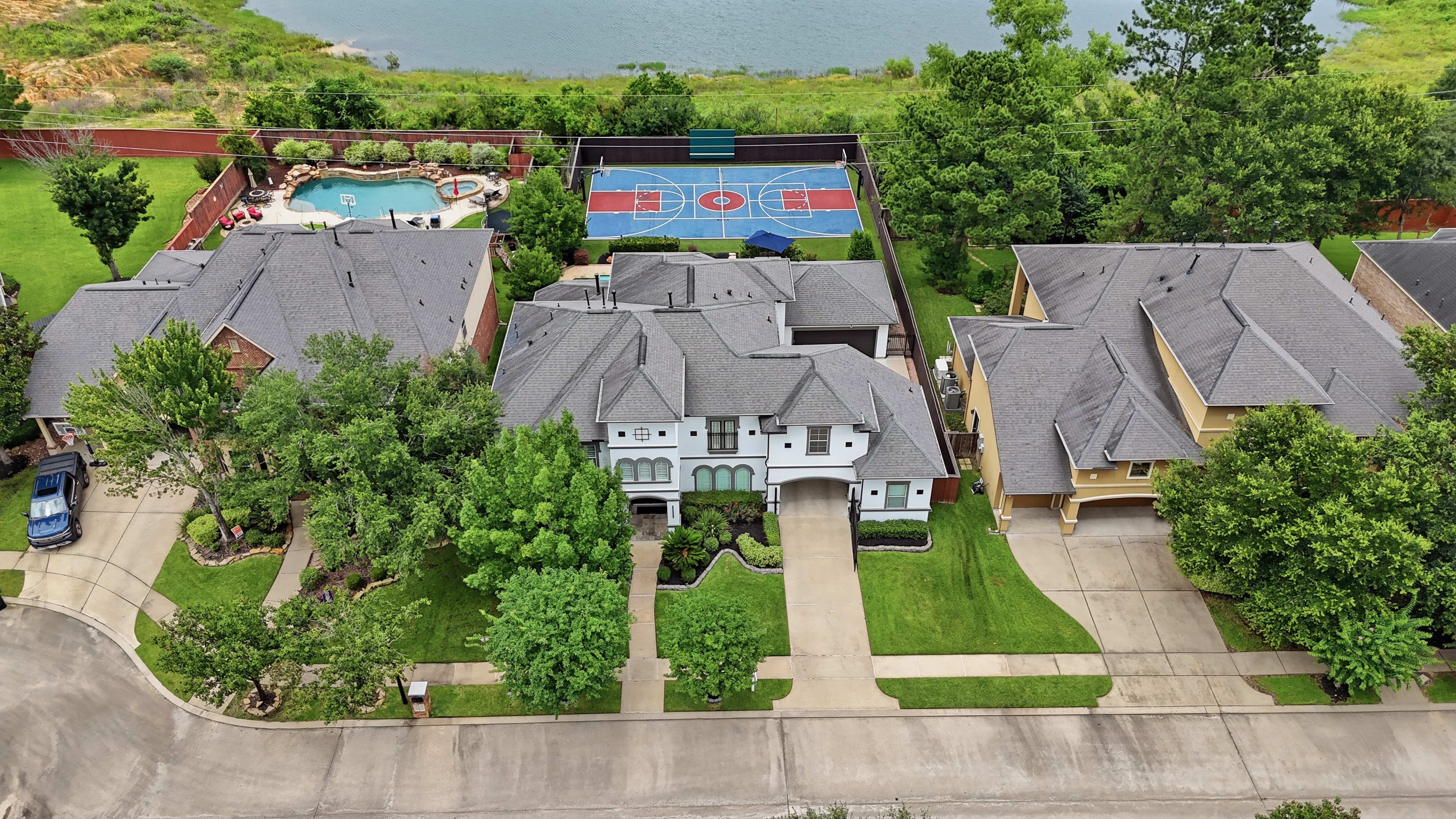 Drone photo of a home's front exterior with the backyard and lake behind it Drone photo of a home's front exterior with the backyard and lake behind it