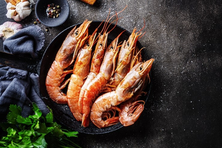 Gros plan de gambas entières fraîches dans une poêle, sélectionnées au marché de Rungis en France pour la gastronomie de produits de la mer.