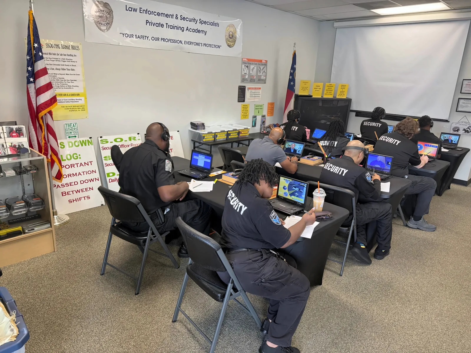 Academy students in security uniforms completing classroom training activities using laptops and instructional materials