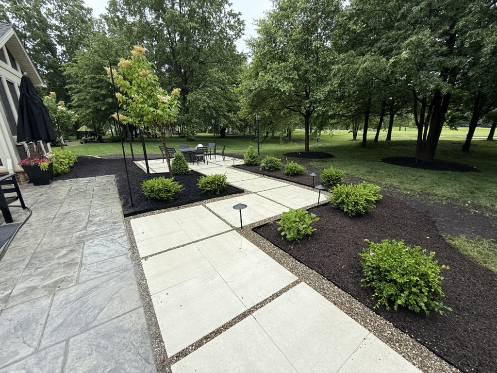 Backyard with new planting beds along a tiled walkway to a patio