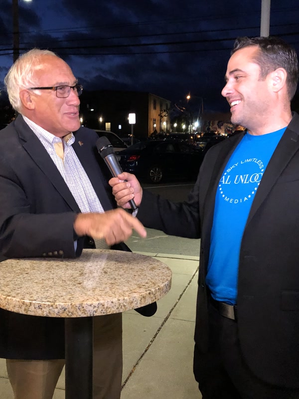 Chris Abazis interviewing a guest with a microphone for Local Unlocked