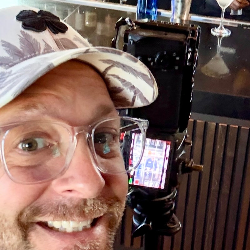 Jon smiling beside his camera on a tripod during a shoot