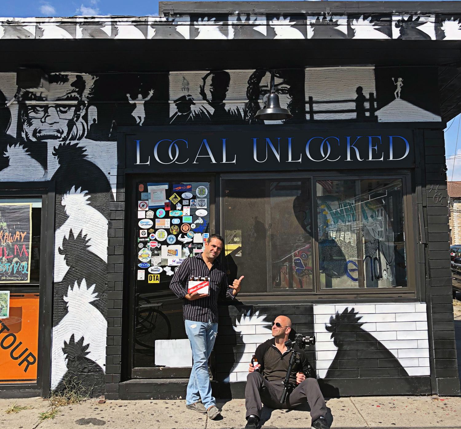 The Local Unlocked crew outside a local business with a mural storefront