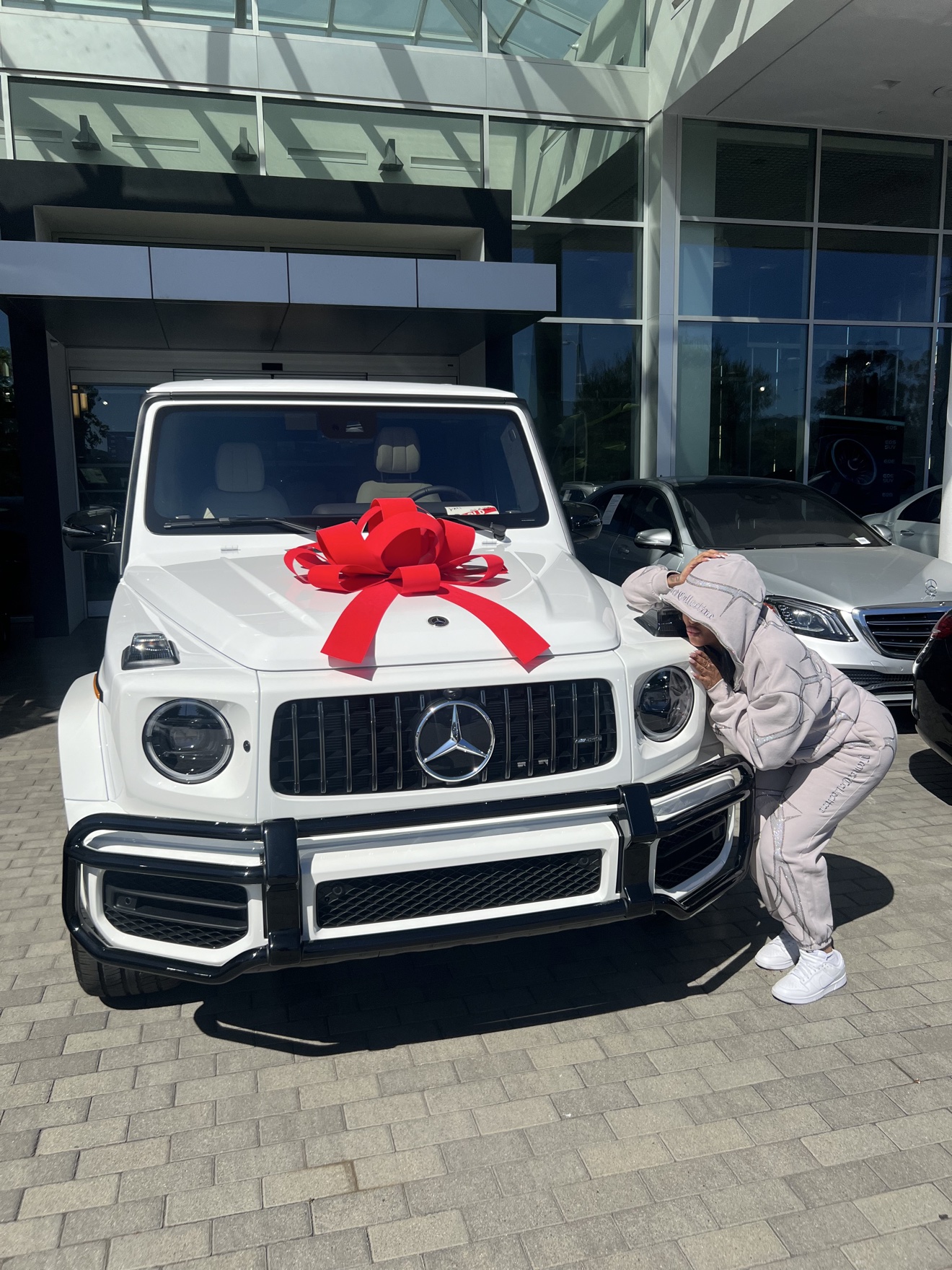 Chelsea beside her white G-Wagon on delivery day, a red bow on the hood