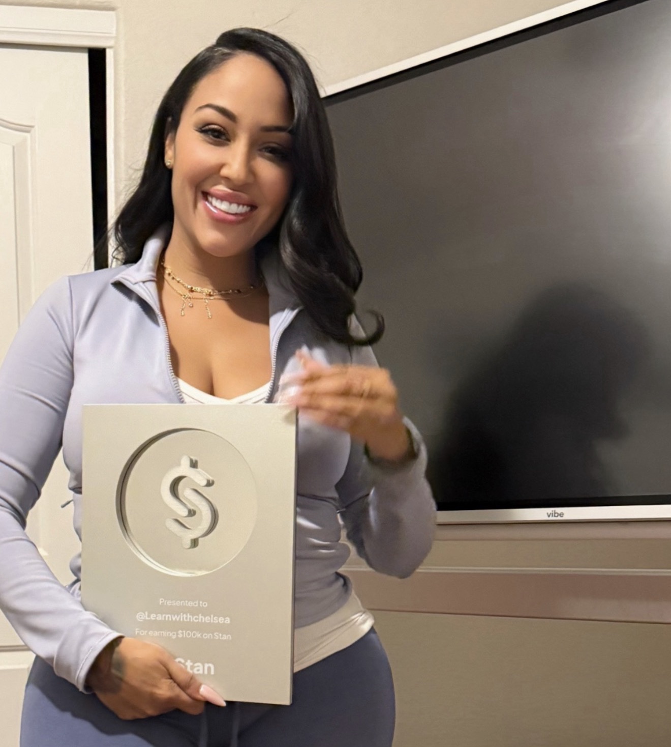 Chelsea Guarriello smiling and holding a Stan award plaque recognizing 100 thousand dollars earned