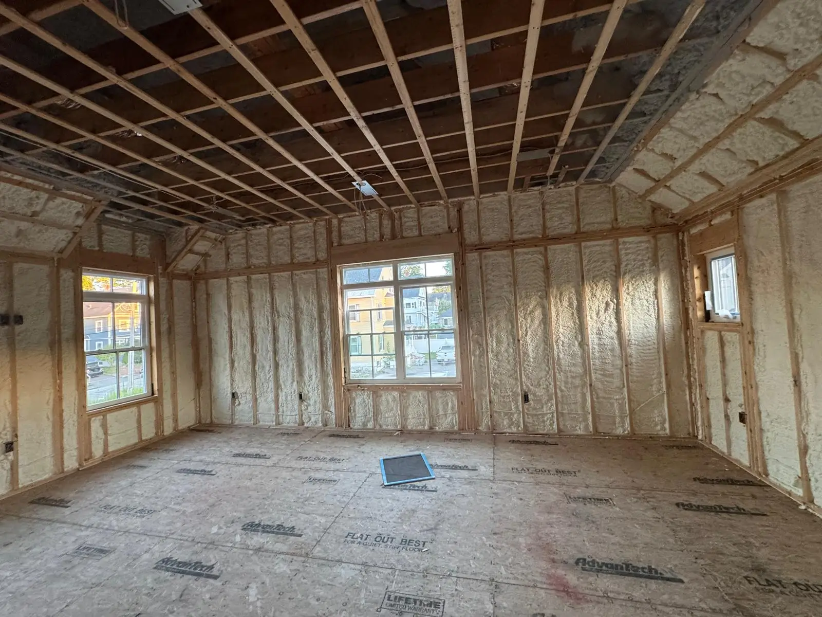 Professional installing fiberglass batt insulation between wooden wall studs in a bright home