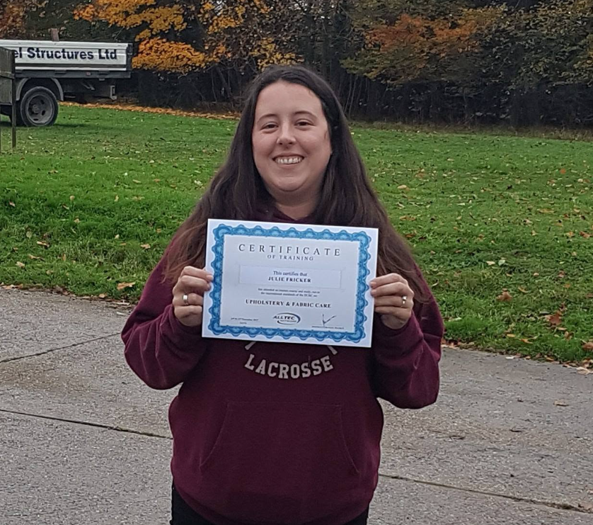 Julie, owner of Spring Clean Homes, holding her professional carpet cleaning certificate