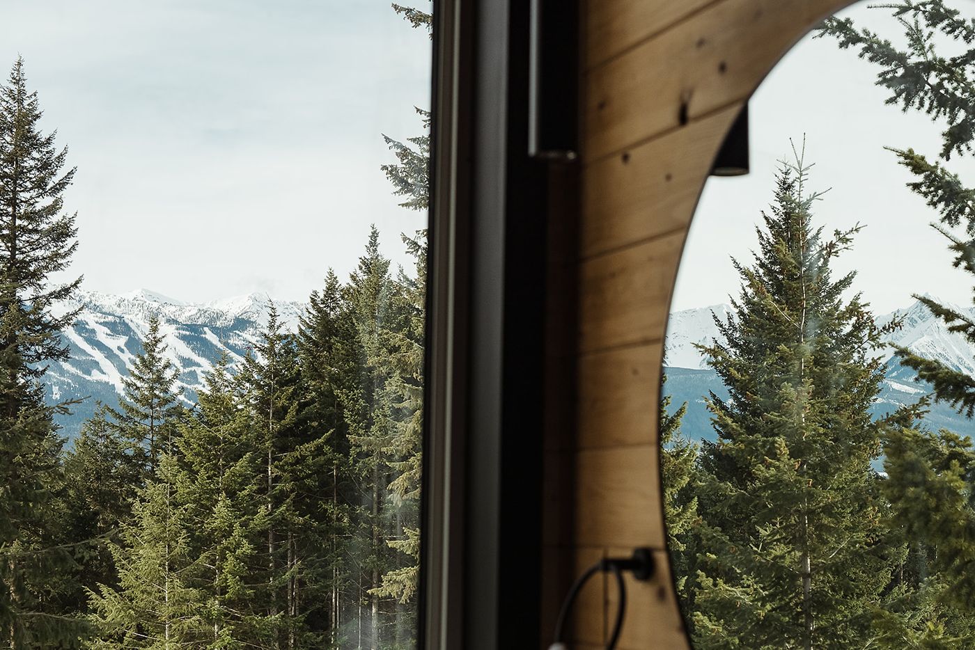 View of snowy mountains and evergreens from a window in Golden, BC
