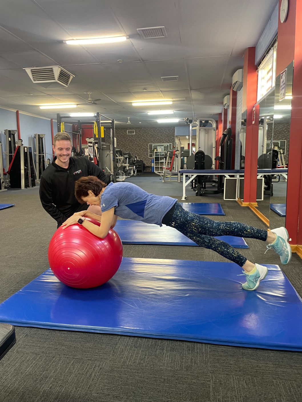An Exercise Physiologist working one-to-one with a client on the floor at Exercise for Life in Bedford.