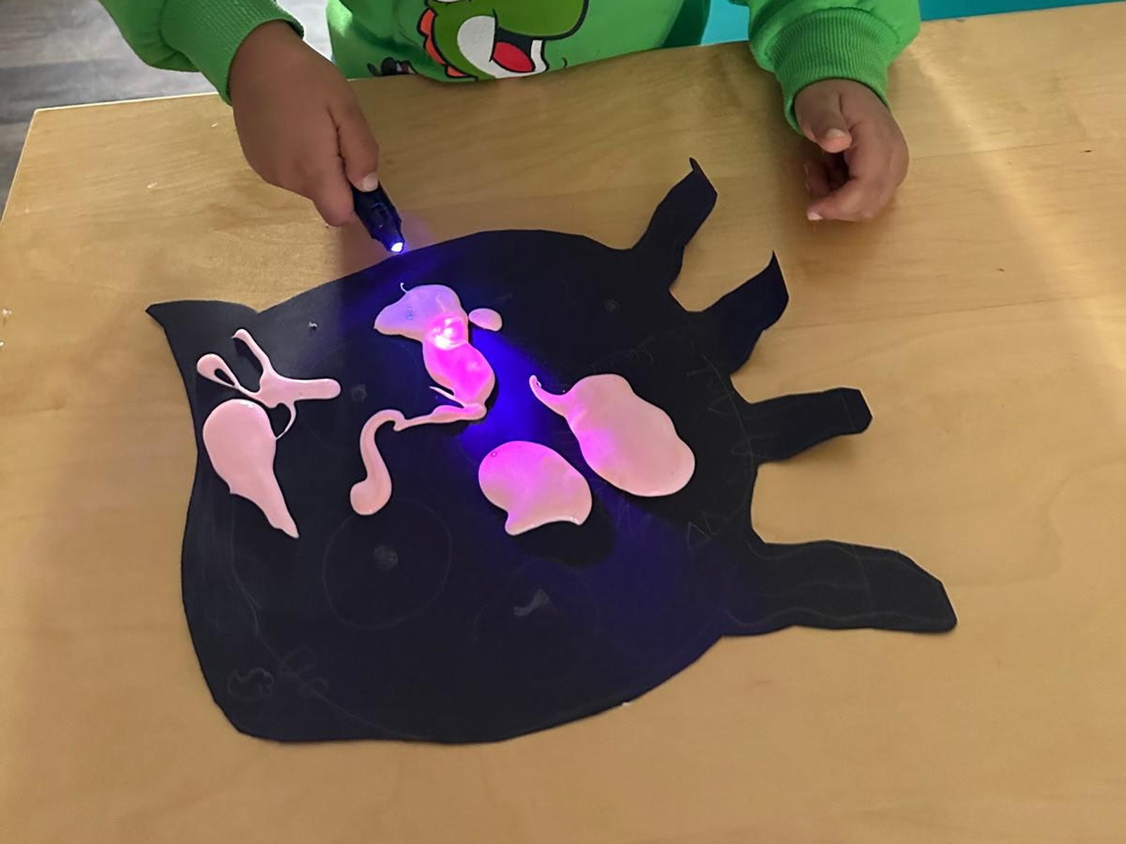A UV light making glowing paint shine on black paper at BioTroopers.